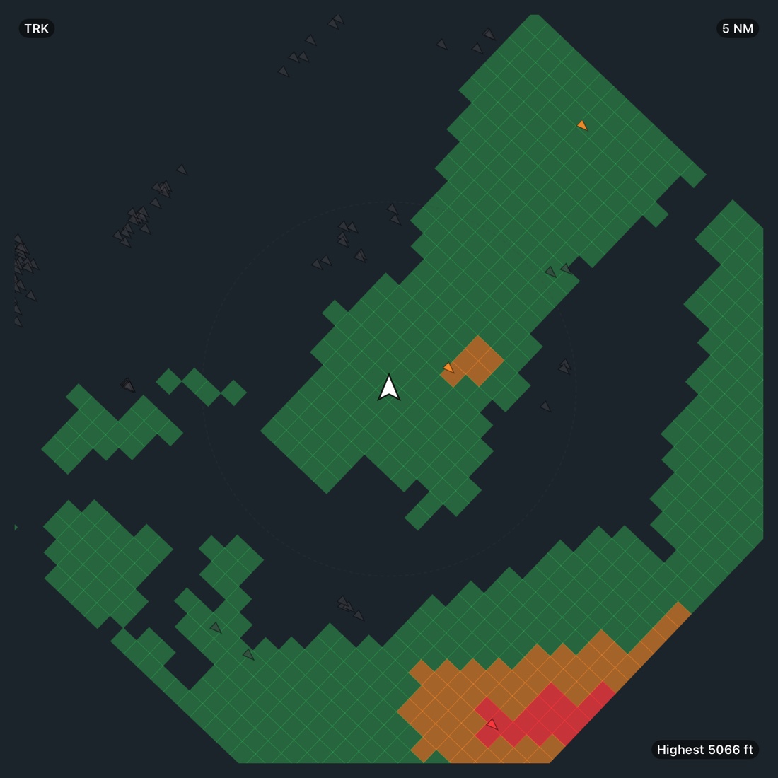The moving map on the terrain layer at 5 NM near Santa Monica: green terrain with an amber patch beside the aircraft, red and amber ridges to the south, and small triangular obstacle marks coloured grey and amber by clearance.